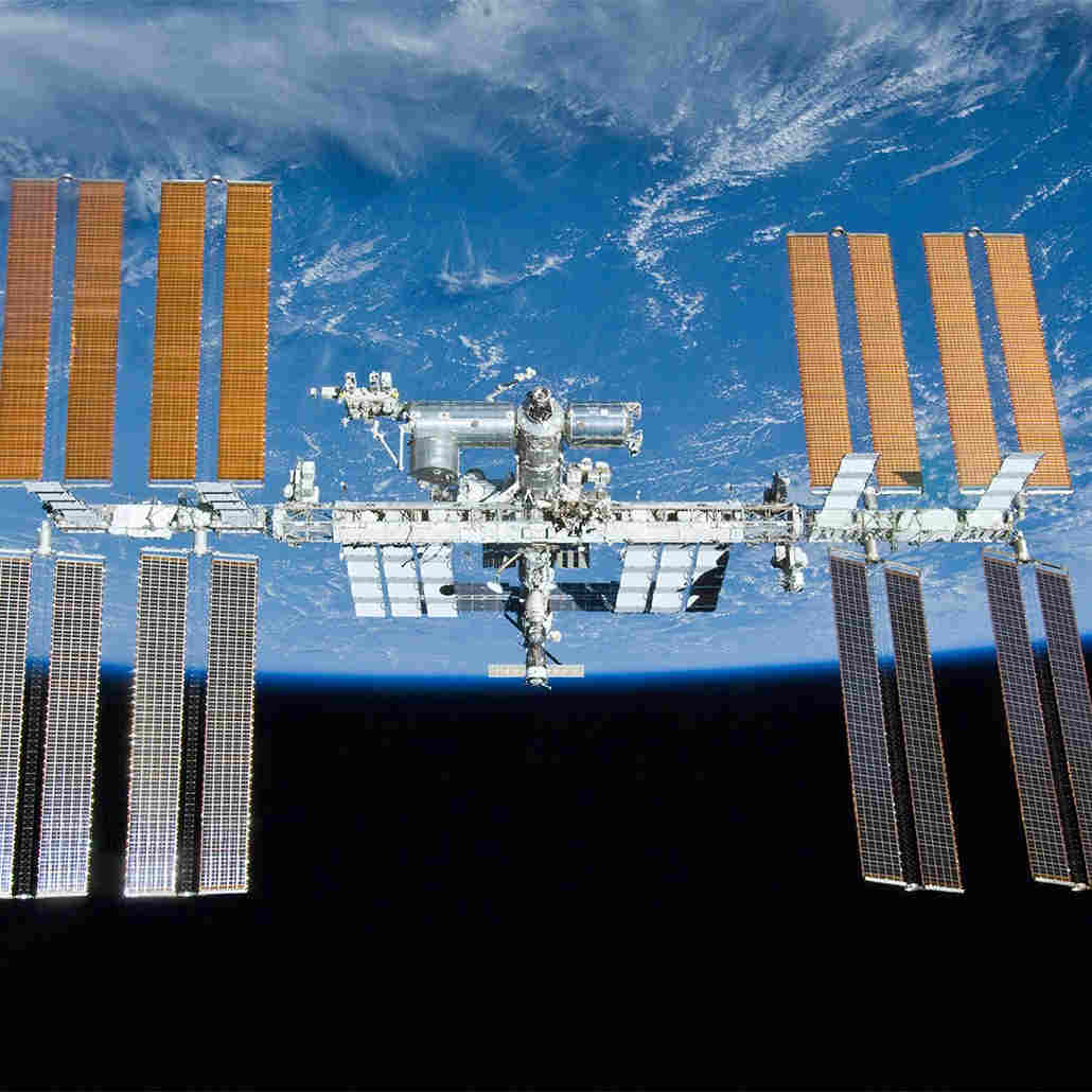 Small circular image of the International Space Station, with Earth in the background. (Source: NASA)